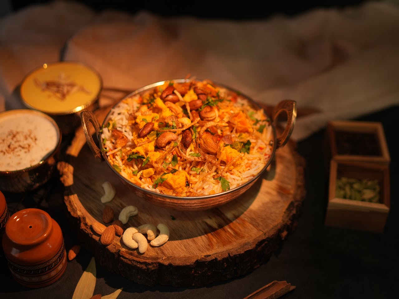 services-02 A flavorful bowl of authentic Indian biryani garnished with fried onions and cashews, served with sides.