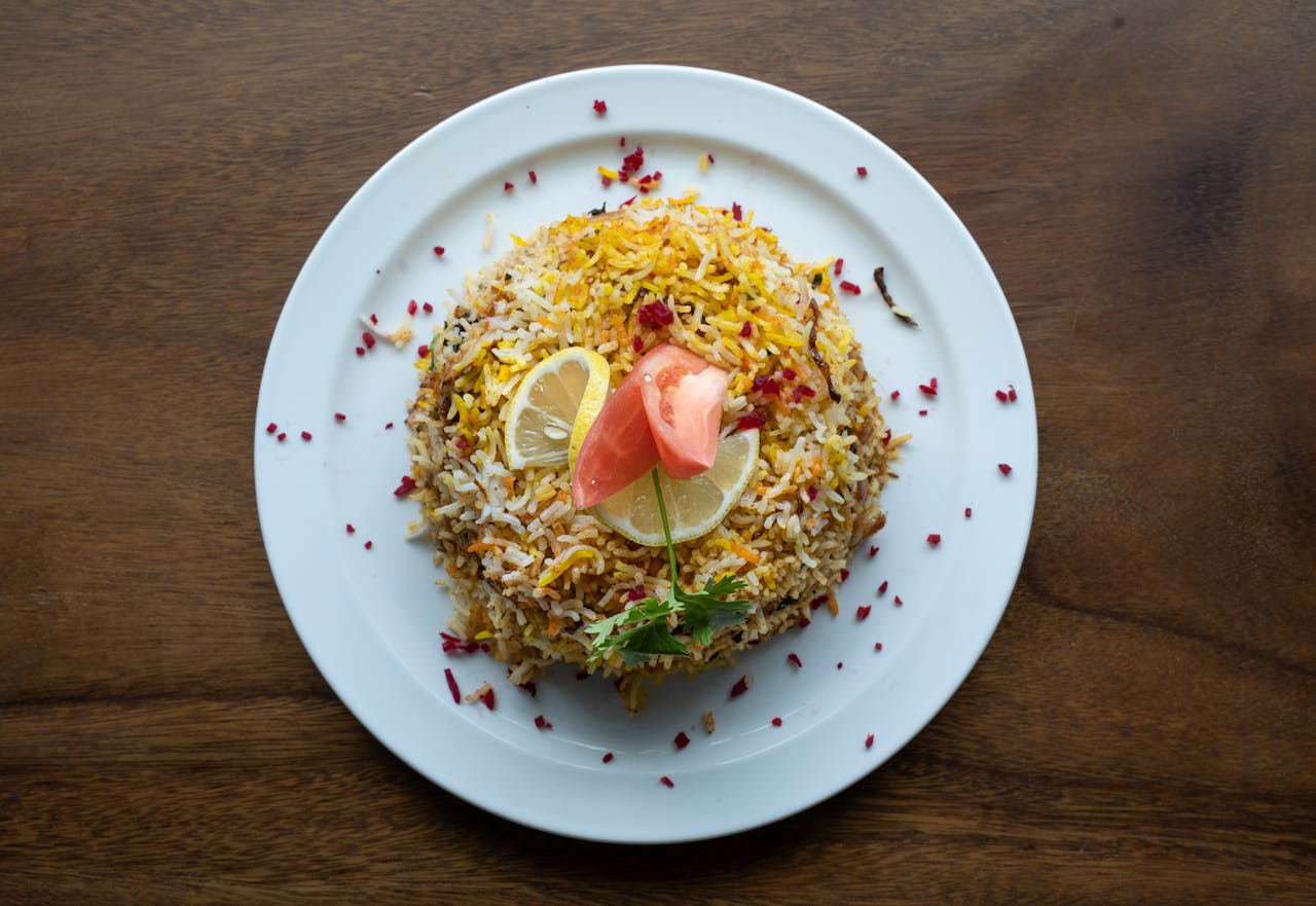 services-03 Top view of Indian biryani with lemon and tomato garnish on a plate, perfect for food photography.